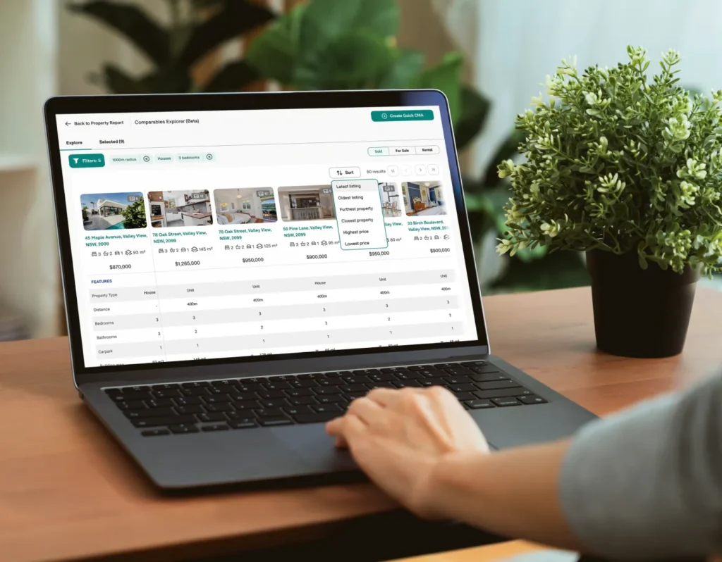Person using a laptop to compare property listings and prices on a real estate platform, with a green plant on the desk nearby.